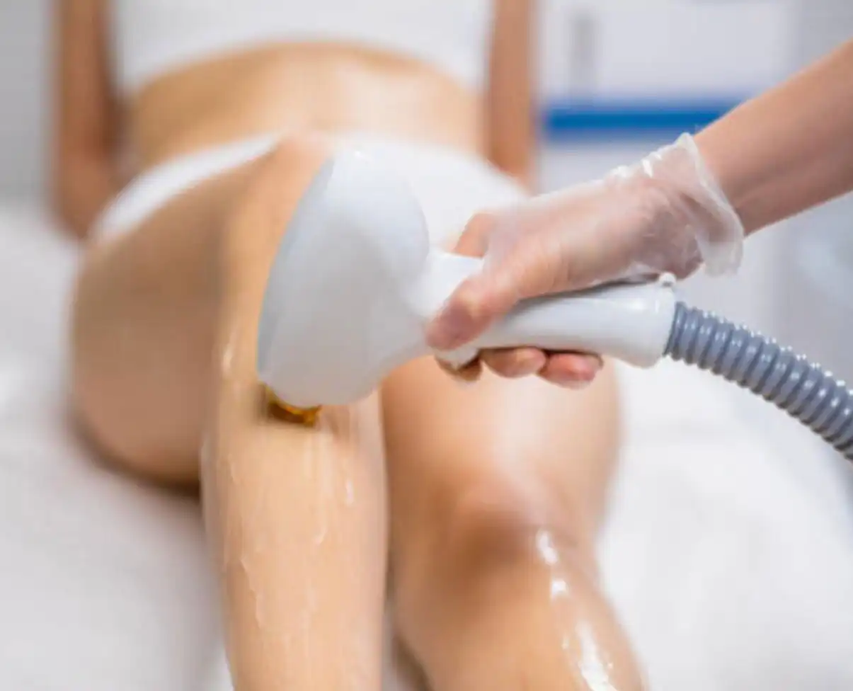 A laser hair remover is being used on a woman's legs